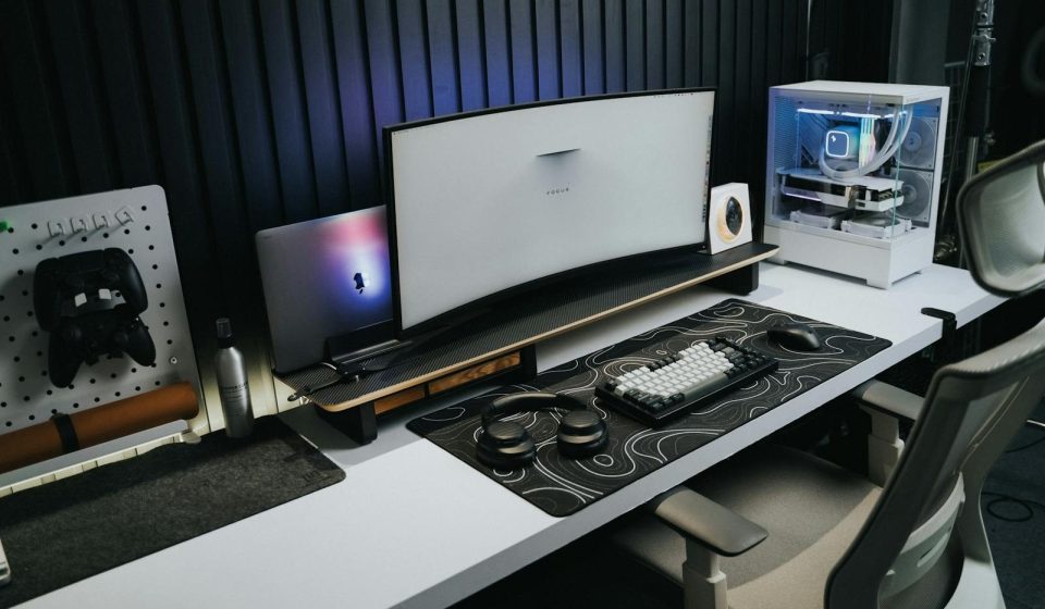 A sleek, modern office setup with a gaming PC, curved monitor, and accessories, ideal for tech enthusiasts.
