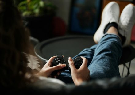 Close-up of woman gaming with a controller, feet propped up, enjoying leisure time indoors.