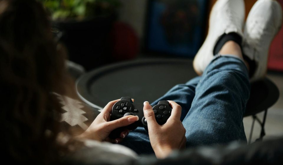 Close-up of woman gaming with a controller, feet propped up, enjoying leisure time indoors.