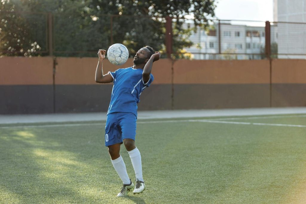 Athlete in blue uniform skillfully heads the soccer ball on a sunny day.