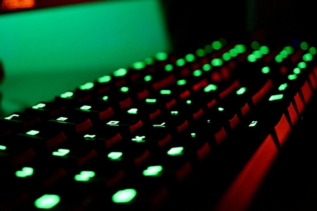 Close-up of a backlit gaming keyboard with vibrant green LED lights creating a glowing effect.