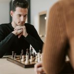 A man intently focuses on his next move during a chess game indoors.