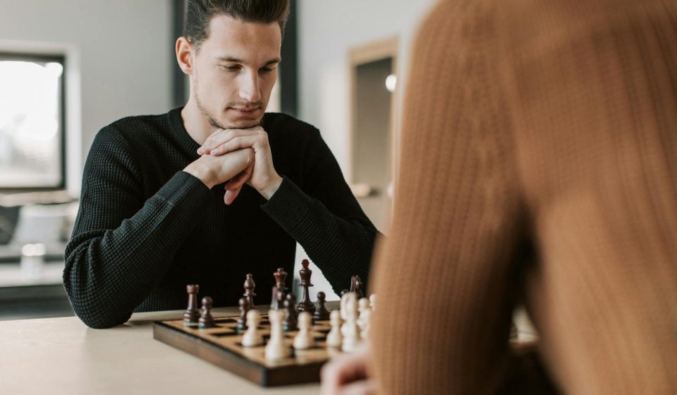 A man intently focuses on his next move during a chess game indoors.