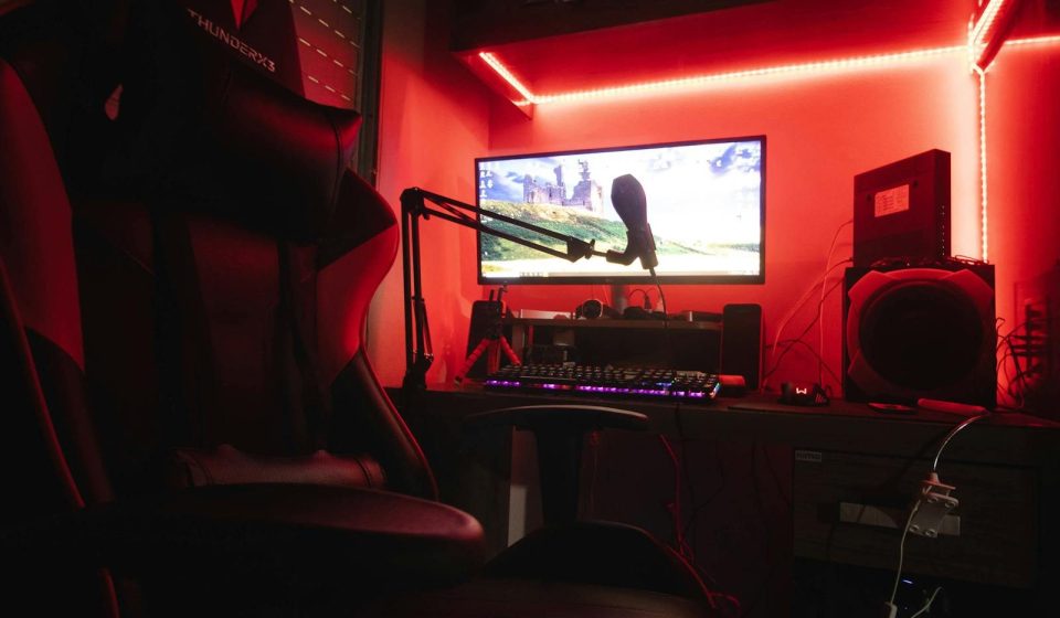 Sleek gaming setup featuring a microphone, neon lights, and a gaming chair in a home studio.