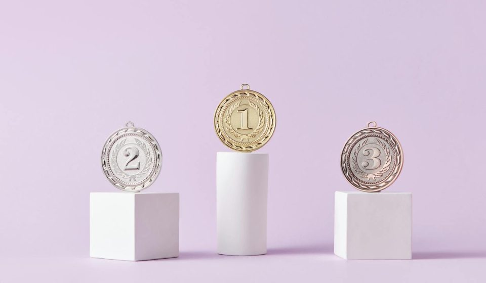 Medals on a podium against a soft pastel background, ideal for awards themes.