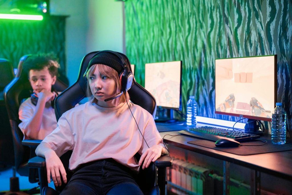 Two teenagers engaged in gaming with headsets in a vibrant neon-lit room.
