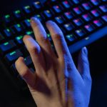 A hand resting on a colorful RGB gaming keyboard, highlighting vibrant illumination.