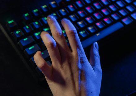 A hand resting on a colorful RGB gaming keyboard, highlighting vibrant illumination.
