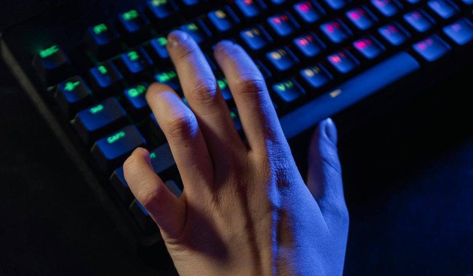 A hand resting on a colorful RGB gaming keyboard, highlighting vibrant illumination.