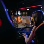 A woman is deeply engaged in playing computer games indoors, highlighting the gaming lifestyle.