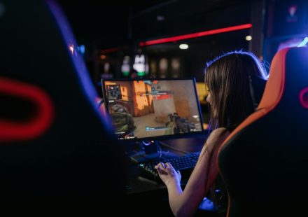 A woman is deeply engaged in playing computer games indoors, highlighting the gaming lifestyle.