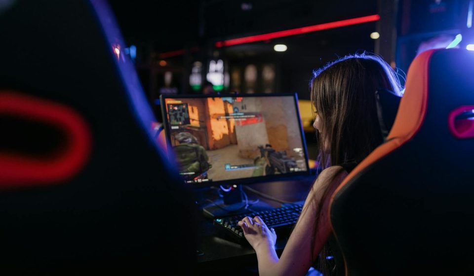 A woman is deeply engaged in playing computer games indoors, highlighting the gaming lifestyle.