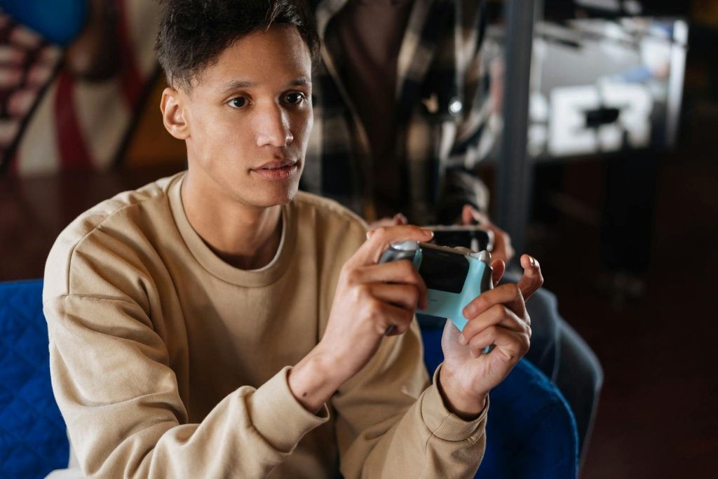 A young man intensely engaged in playing a video game indoors.