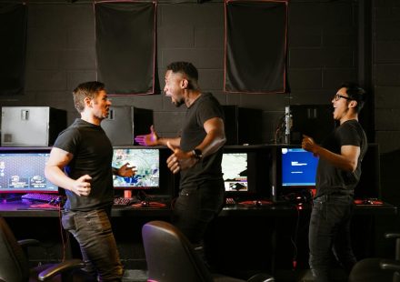 Enthusiastic group of diverse friends celebrating a gaming victory in an esports setting.