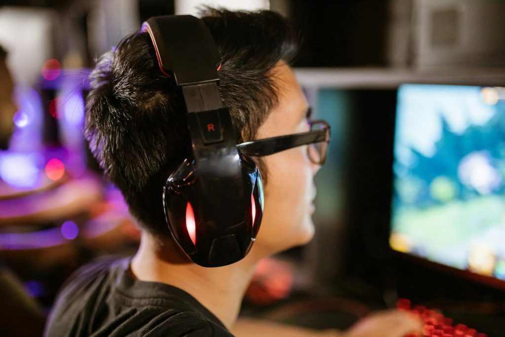 A young gamer wearing headphones intensely focuses on his computer screen.