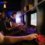 Young adults gaming at a modern LAN center with advanced PCs, showcasing intense gaming focus.