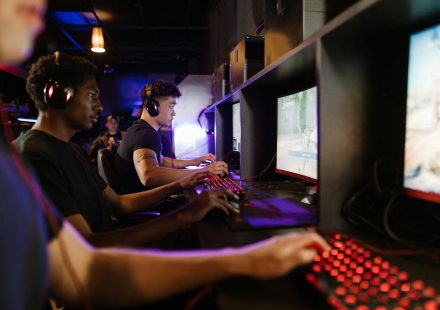 Young adults gaming at a modern LAN center with advanced PCs, showcasing intense gaming focus.