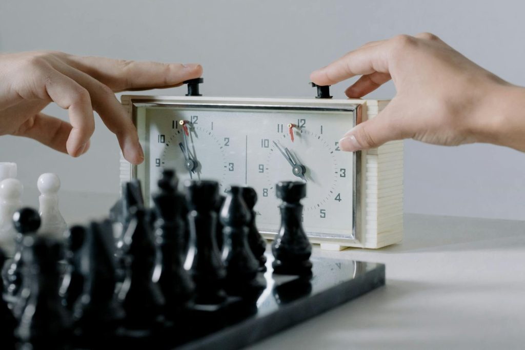 Close-up of hands pressing chess clock during an intense board game session.