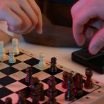 Close-up of hands playing a chess game, capturing strategic moves and intense focus.