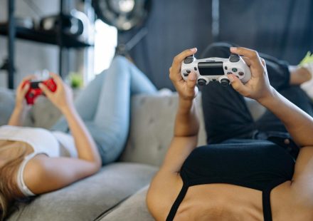 Two women relaxing and playing video games on a couch in a cozy living room.