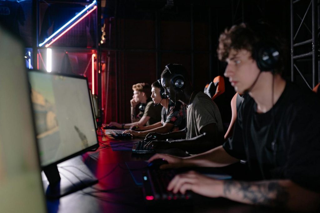 Group of diverse gamers playing in an esports tournament with headsets and screens.