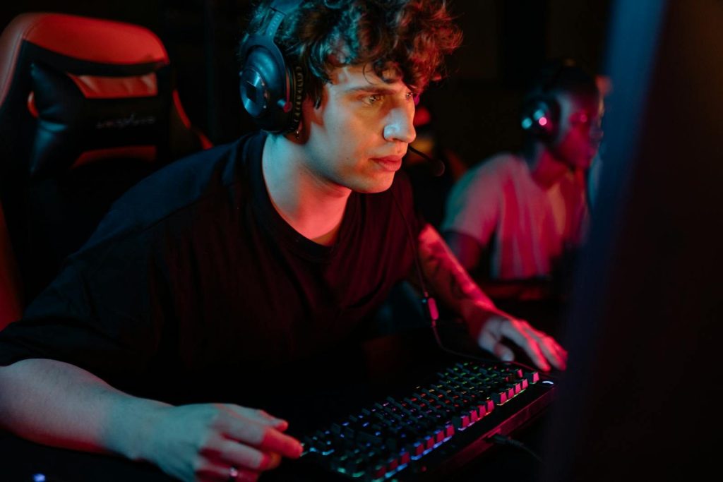 A dedicated gamer immersed in a gaming session with colorful lighting and headphones.