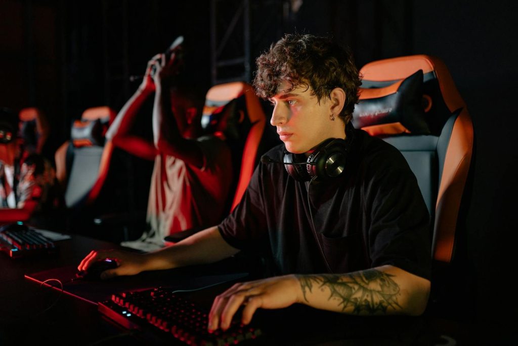 Competitive gamers in an esports tournament concentrating deeply in dimly lit setting.